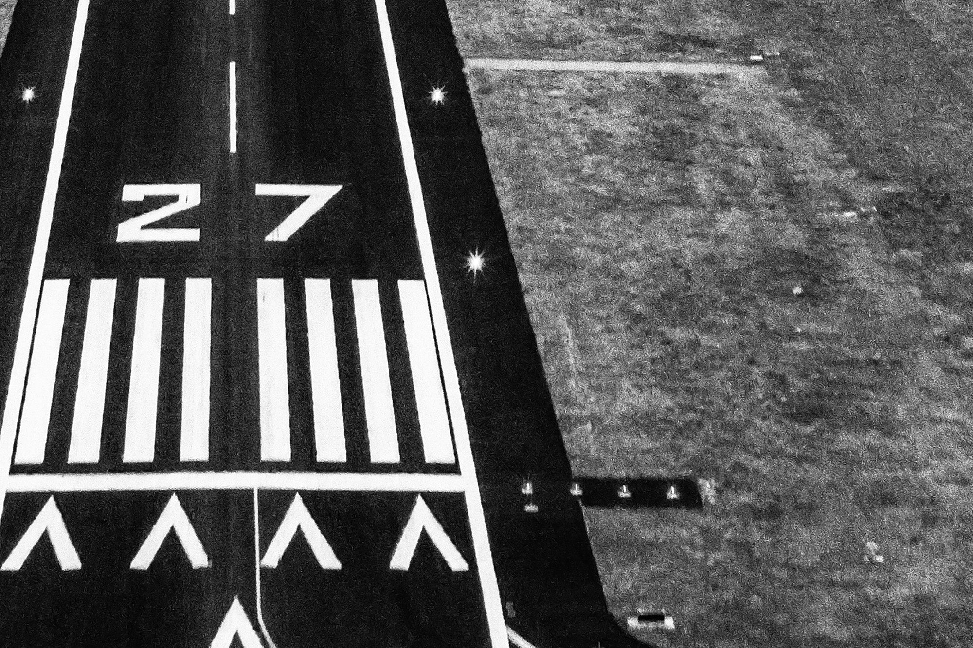 Black and white image of an airport runway with visible markings