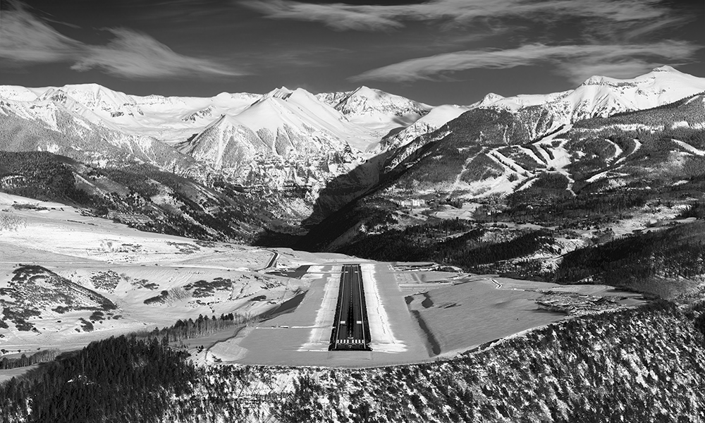 Aerial view of Telluride airport runway with snow & Telluride ski resort and Ajax peak with snow in background