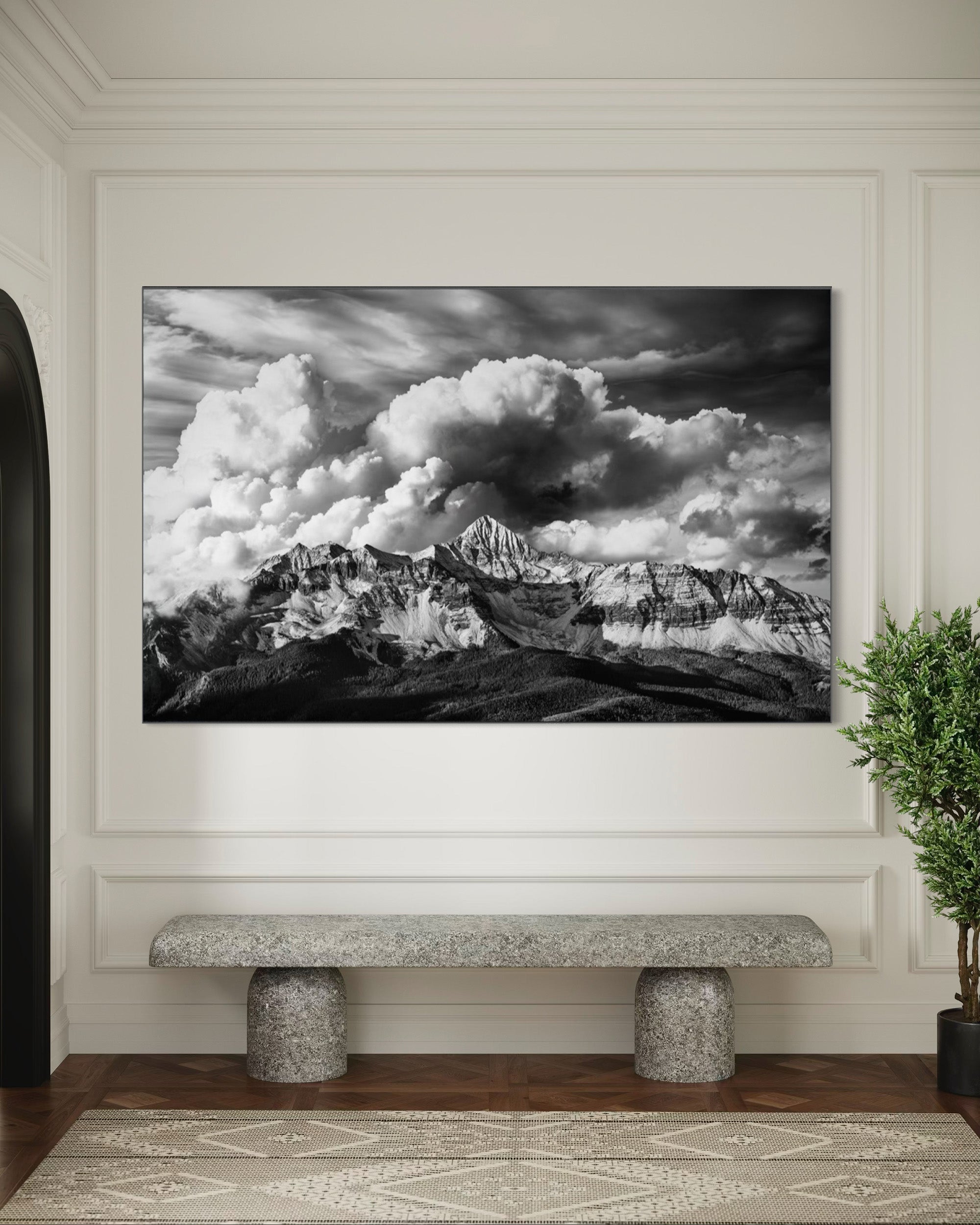 Large black and white mountain landscape photo of Wilson Peak on a wall above a stone bench.